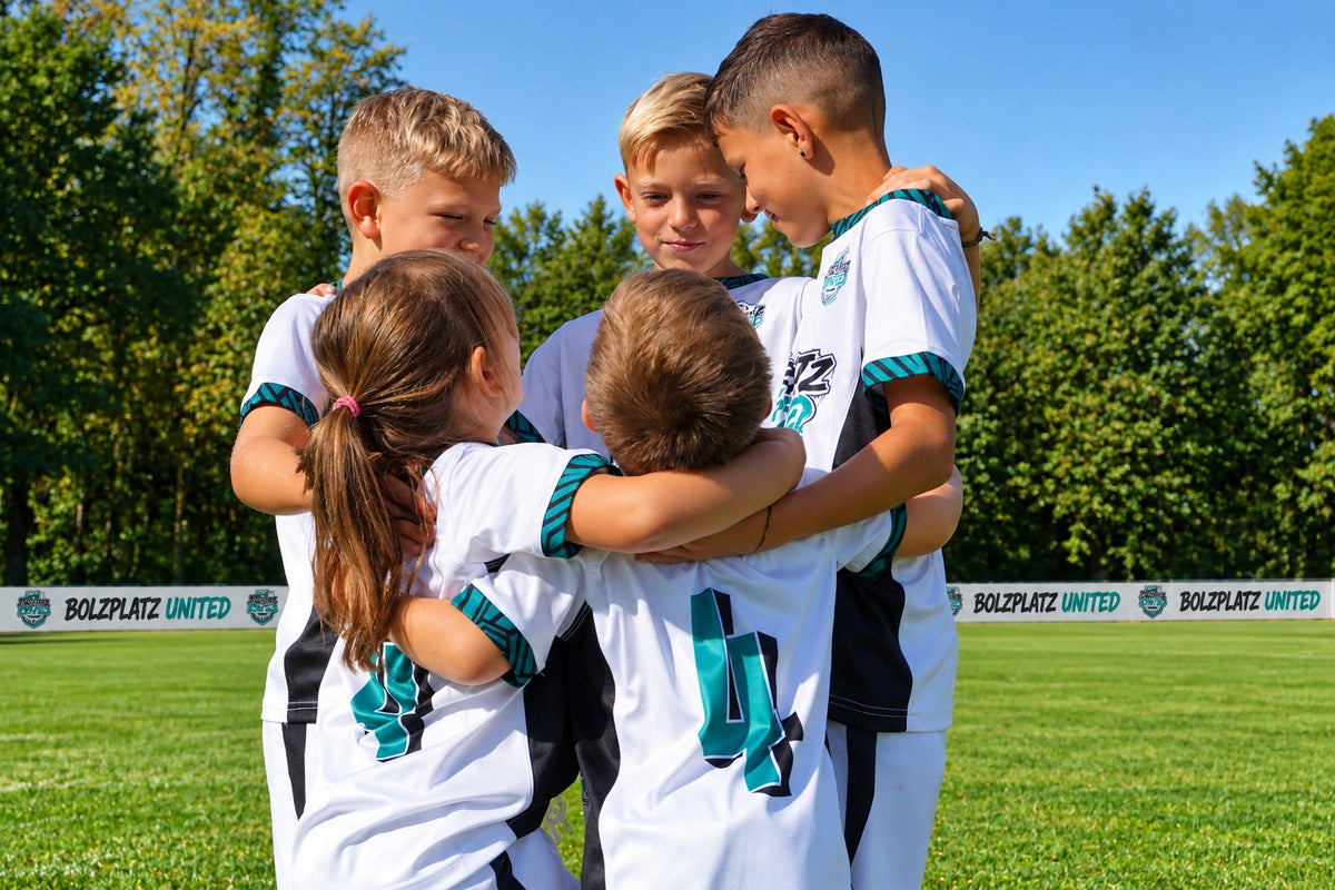Kinder im Bolzplatz United Trikot umarmen sich