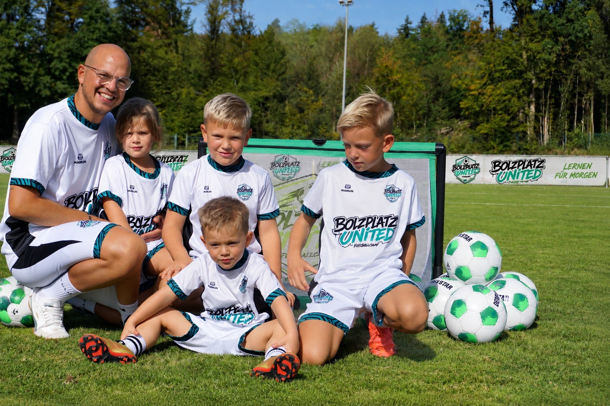 Trainer mit Kindern im Bolzplatz United Trikot vor einem Minitor